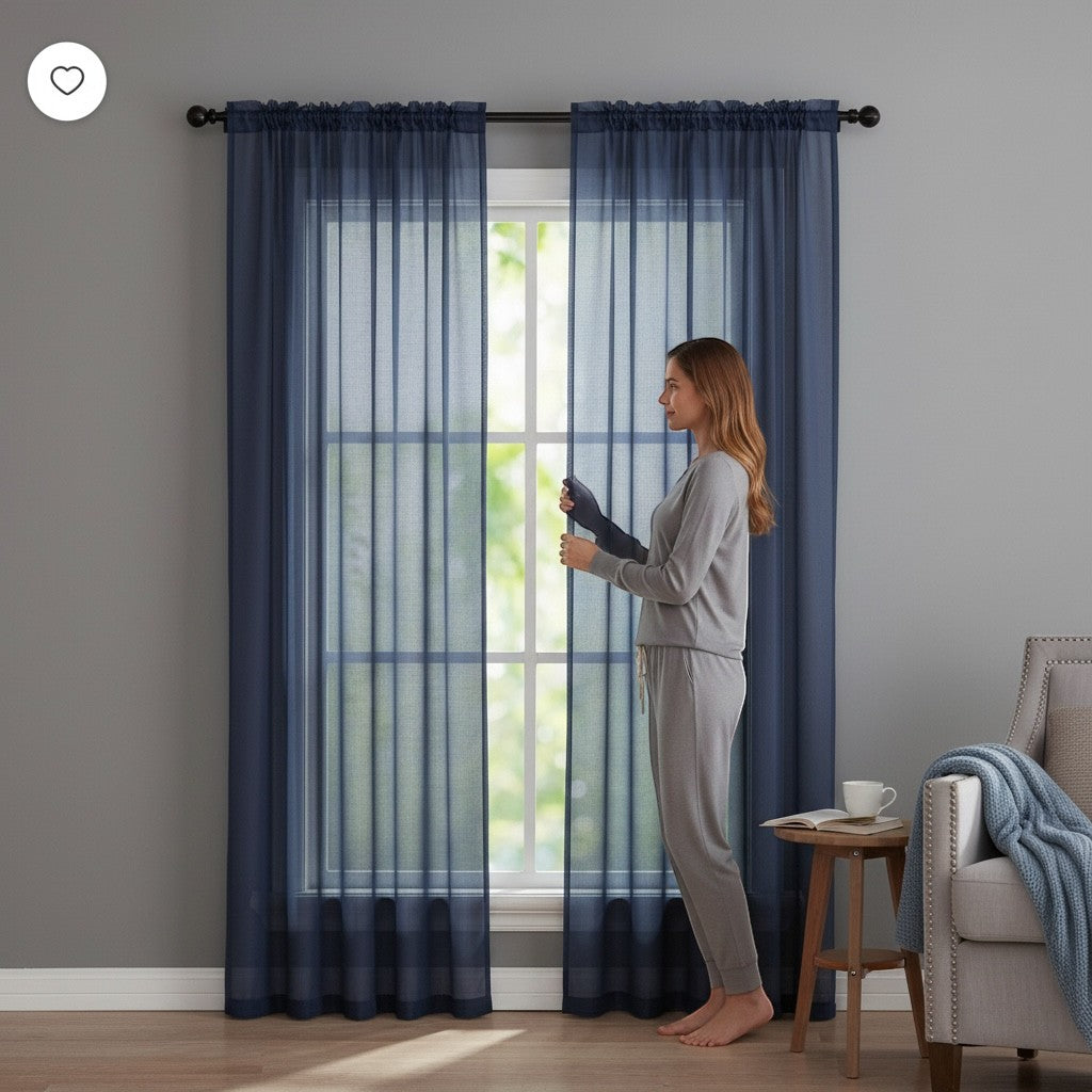 Home Appeal navy blue sheer window curtain panels hanging on a rod in a modern living room with a woman standing nearby.